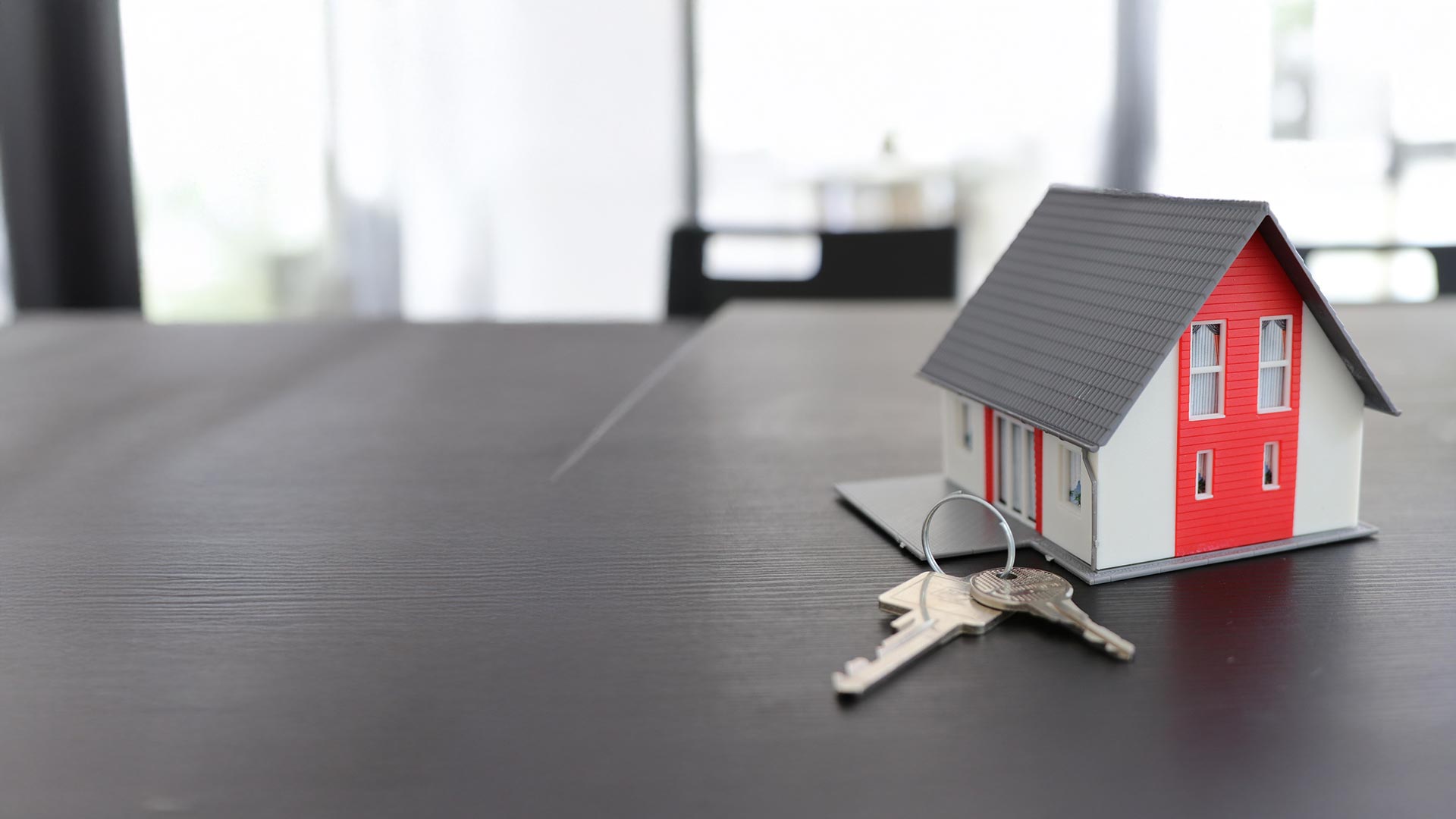 Modello di casa con chiavi su un tavolo – informazioni per i proprietari di immobili sul collegamento alla rete in fibra ottica FTTH di Chiasso4net